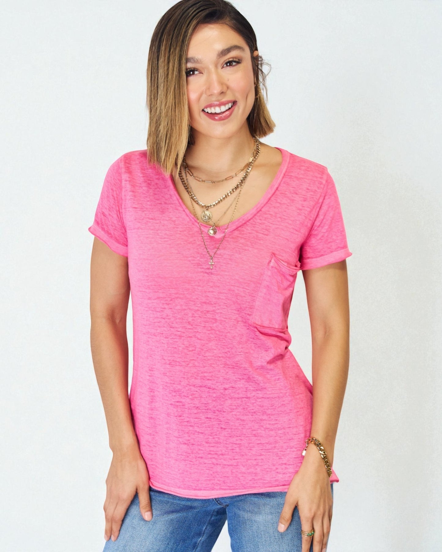 Woman wearing a bright pink t-shirt and blue jeans on a white background