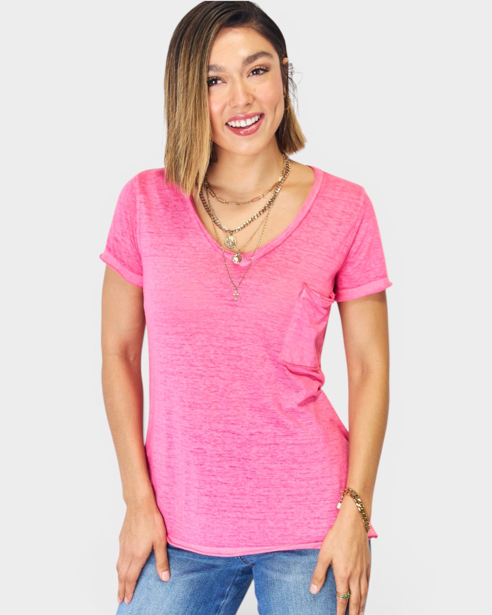 Woman wearing a pink V-neck t-shirt and blue jeans on a white background