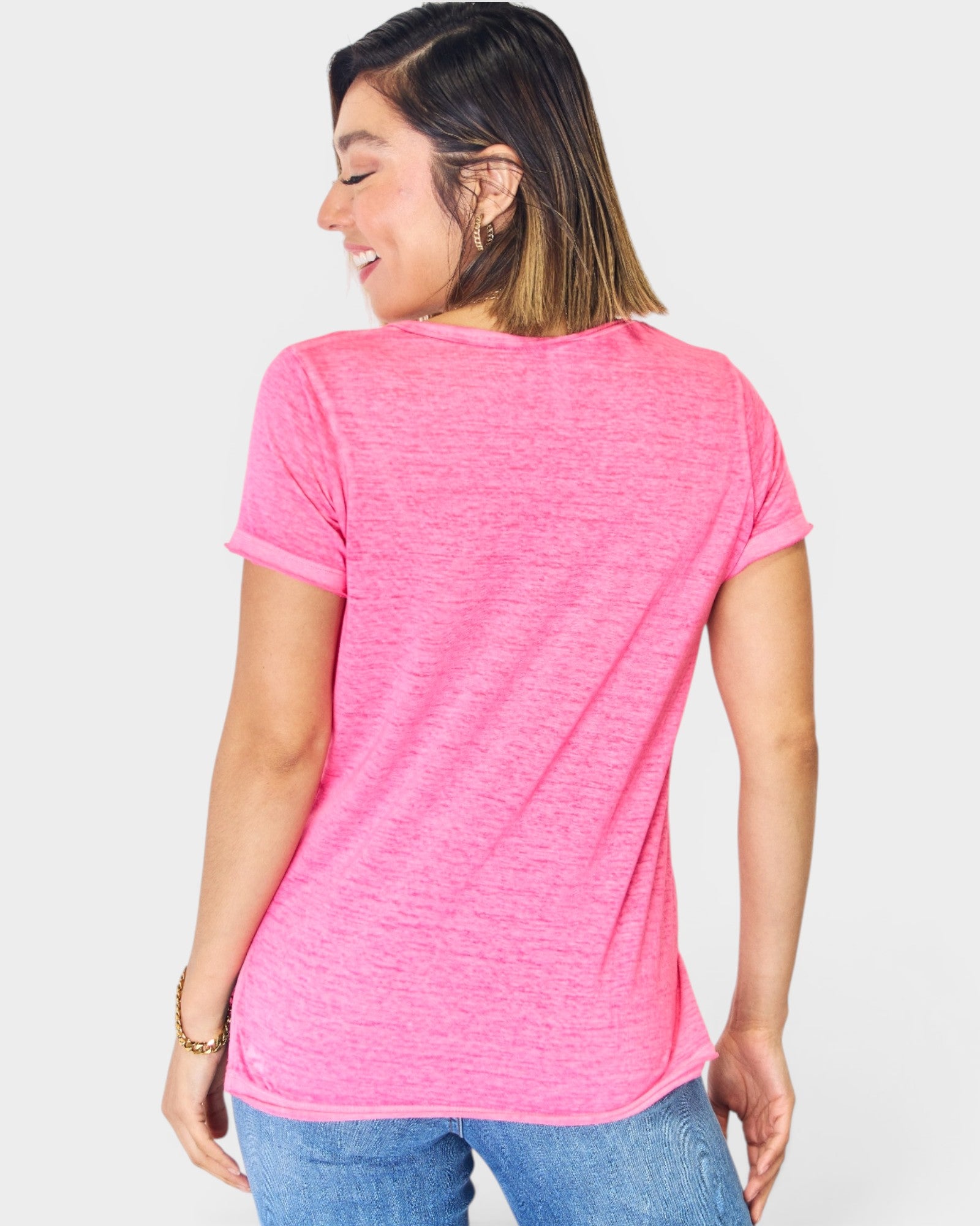 Woman wearing a pink t-shirt and blue jeans on a white background