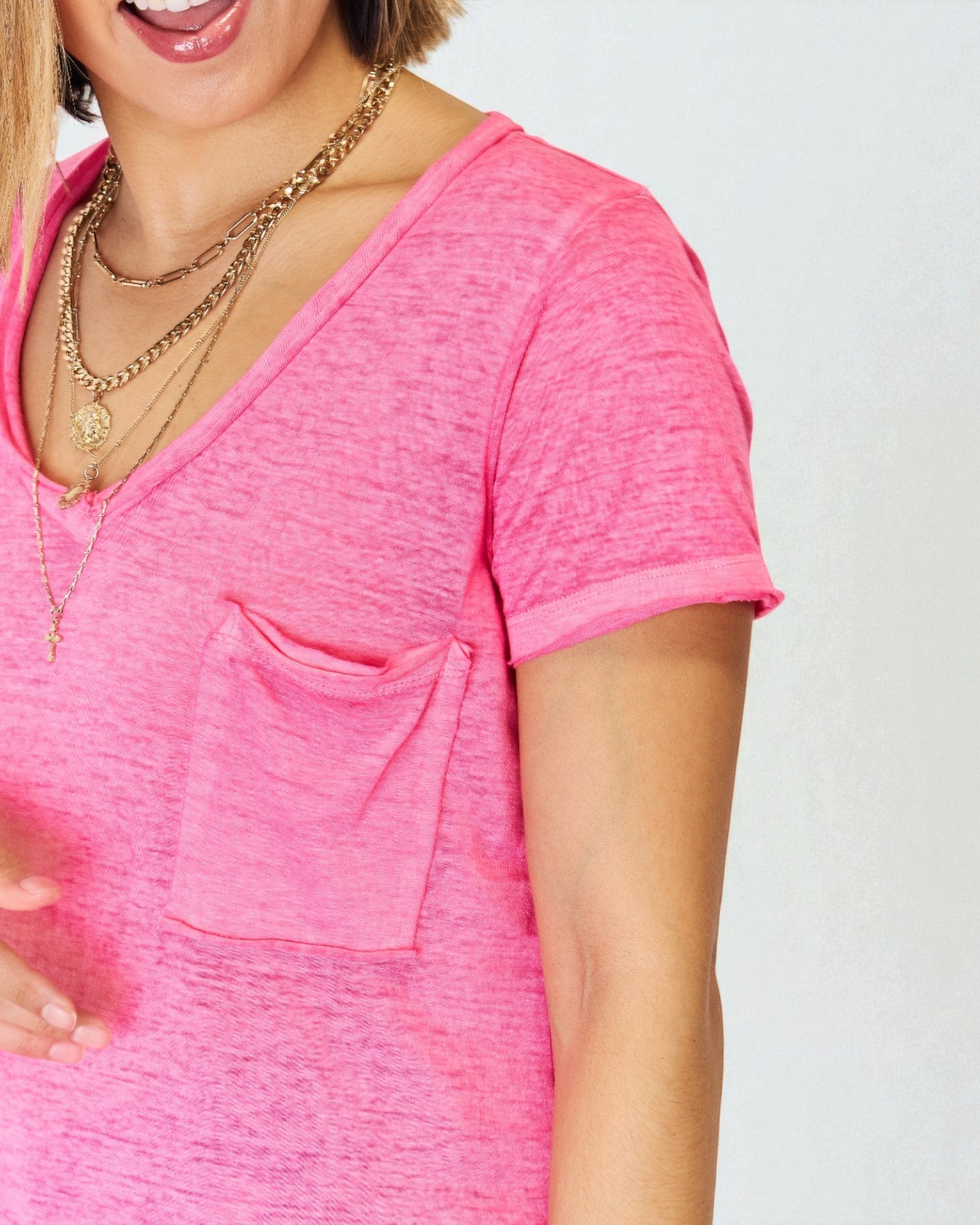Person wearing a bright pink shirt with a pocket on a plain background