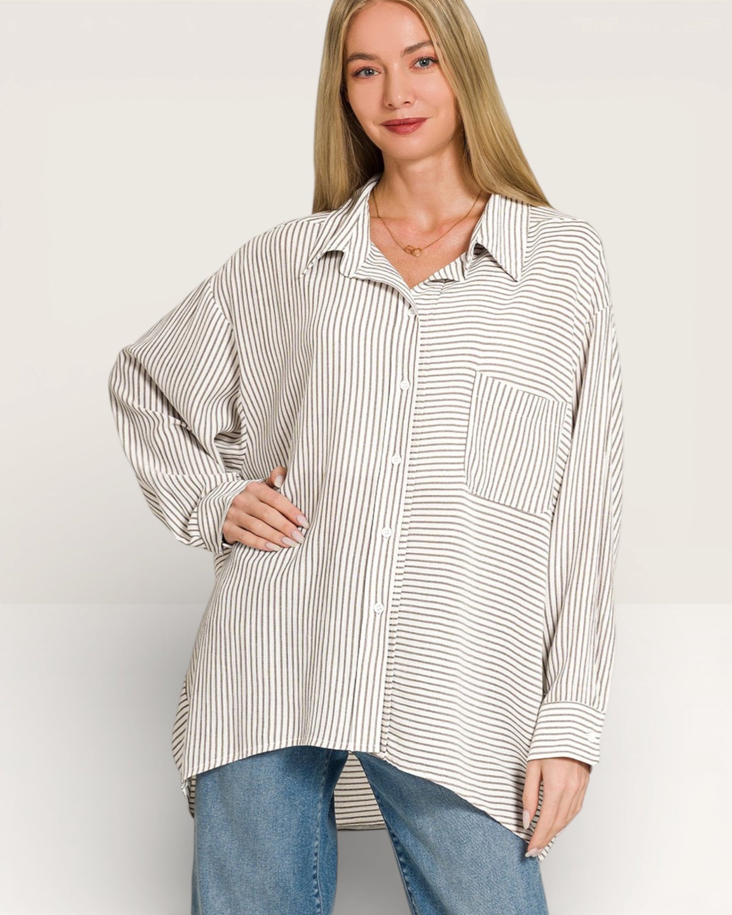 Woman wearing a striped shirt and jeans on a plain background