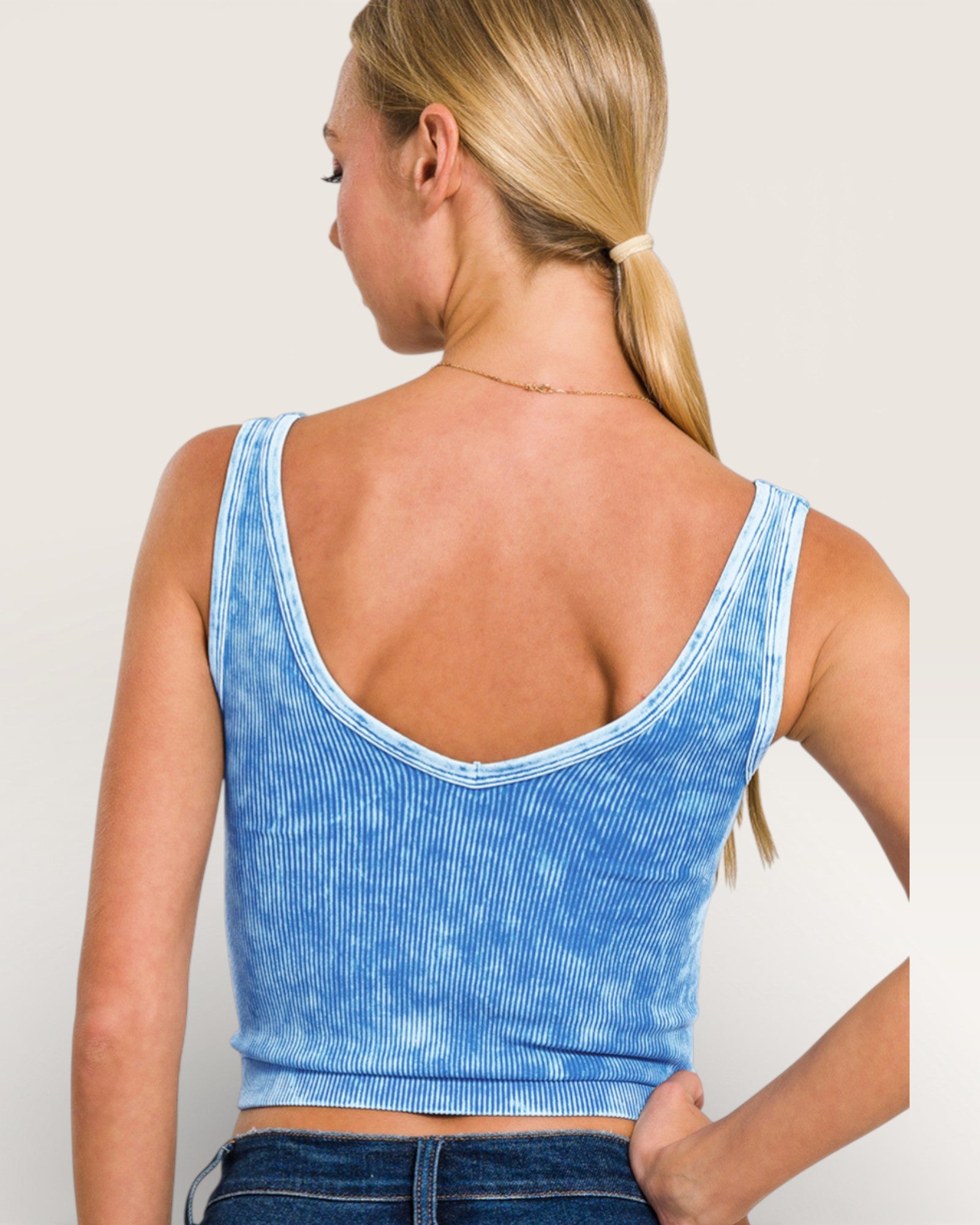 Woman wearing a blue acid-wash crop top against a plain background
