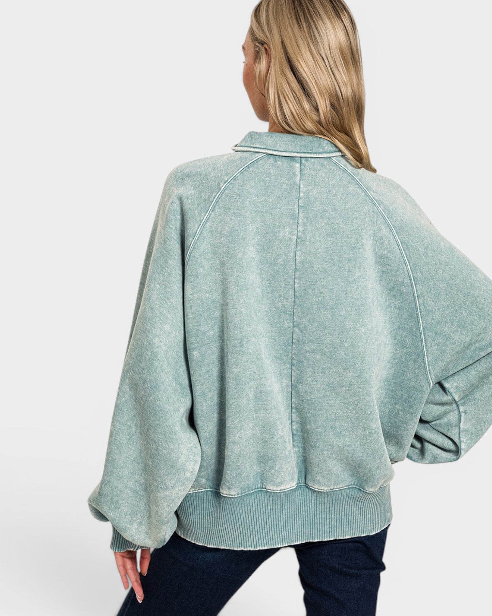 Person wearing a light green sweater with a plain background