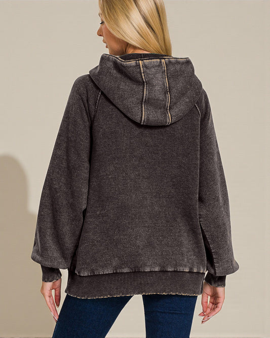 Person wearing a dark gray hooded jacket on a plain background