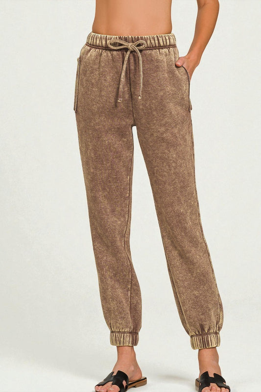 Brown sweatpants worn by a person on a white background