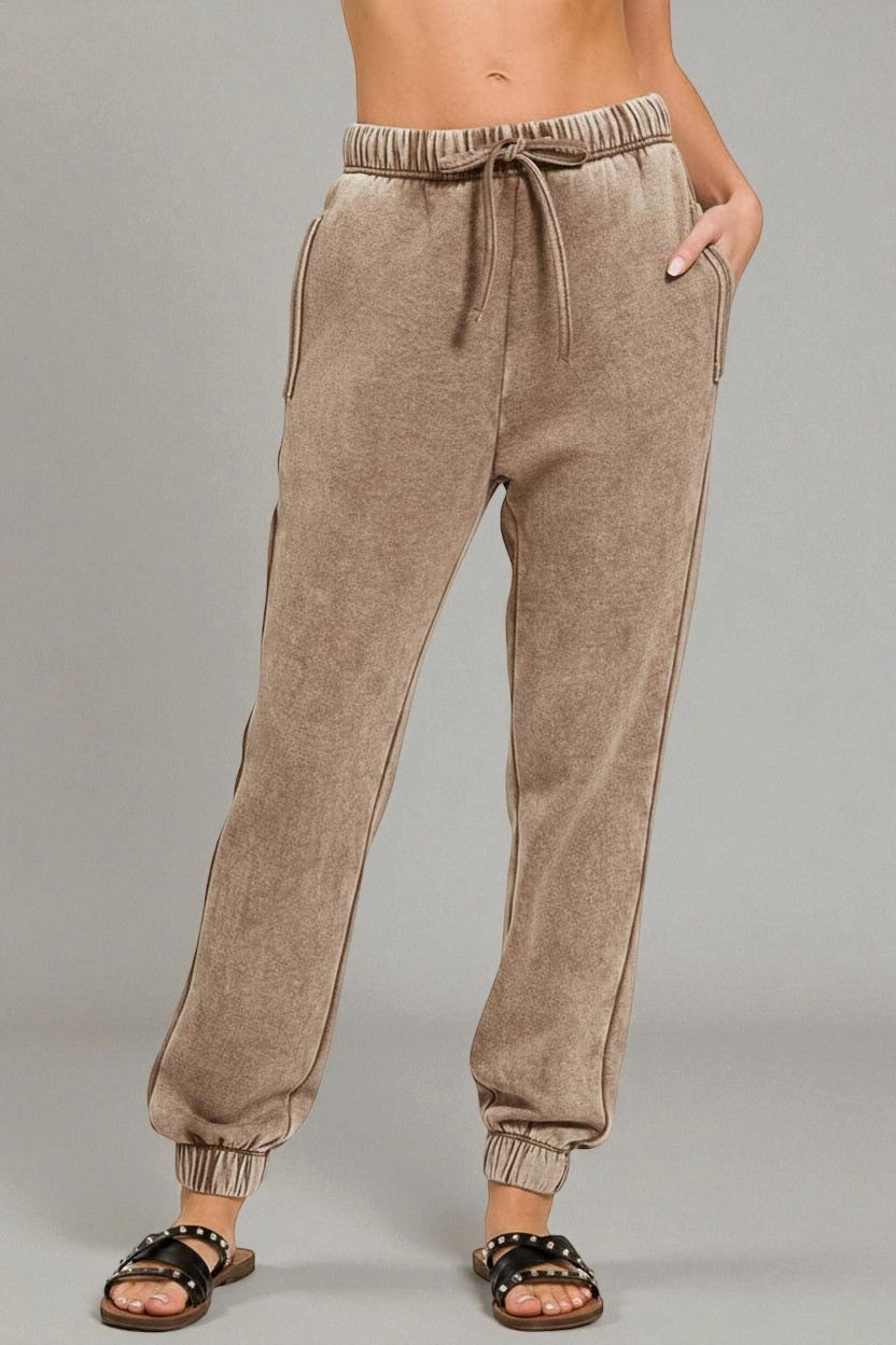 Beige sweatpants worn by a person on a gray background