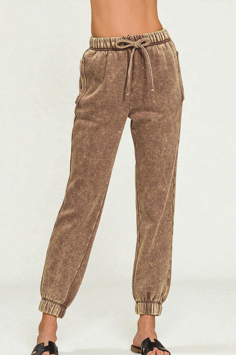 Brown jogger pants worn by a person on a white background