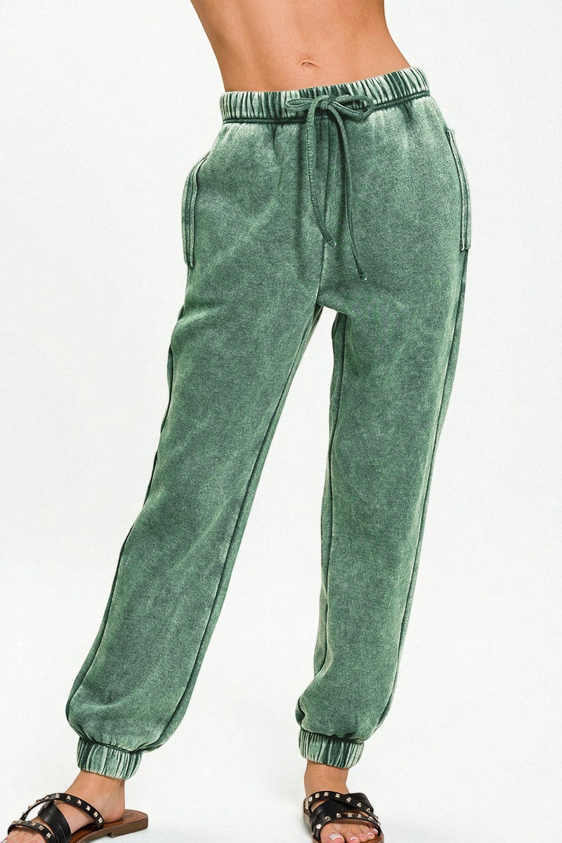 Green sweatpants worn by a person on a white background