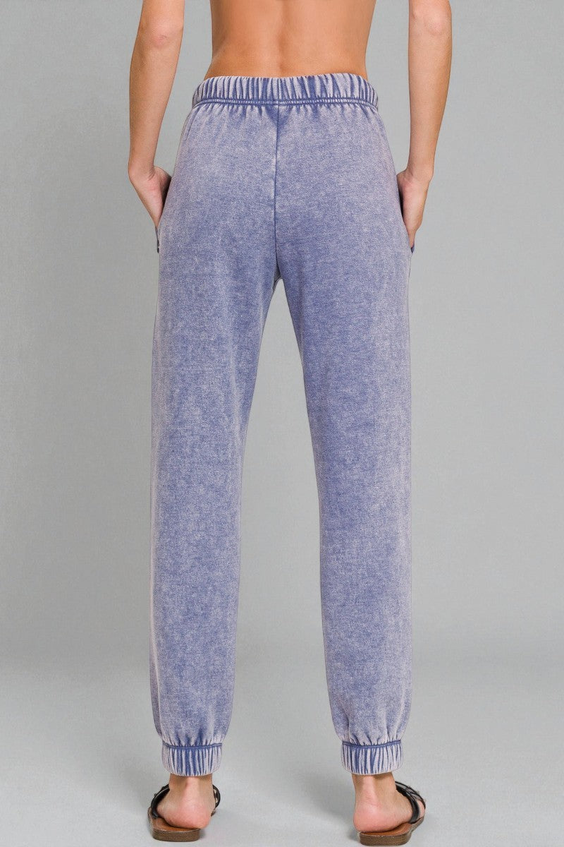Blue jogger pants worn by a person on a gray background