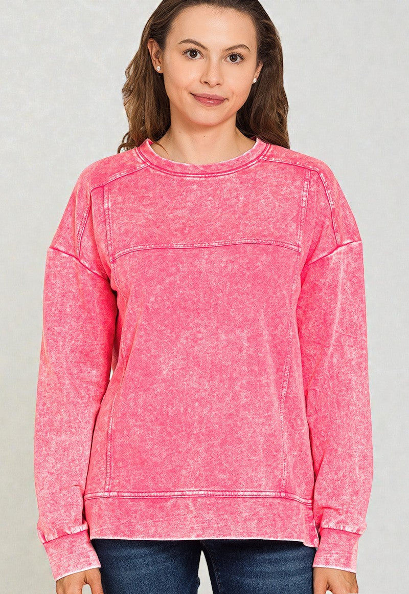 Woman wearing a pink distressed sweatshirt against a plain background