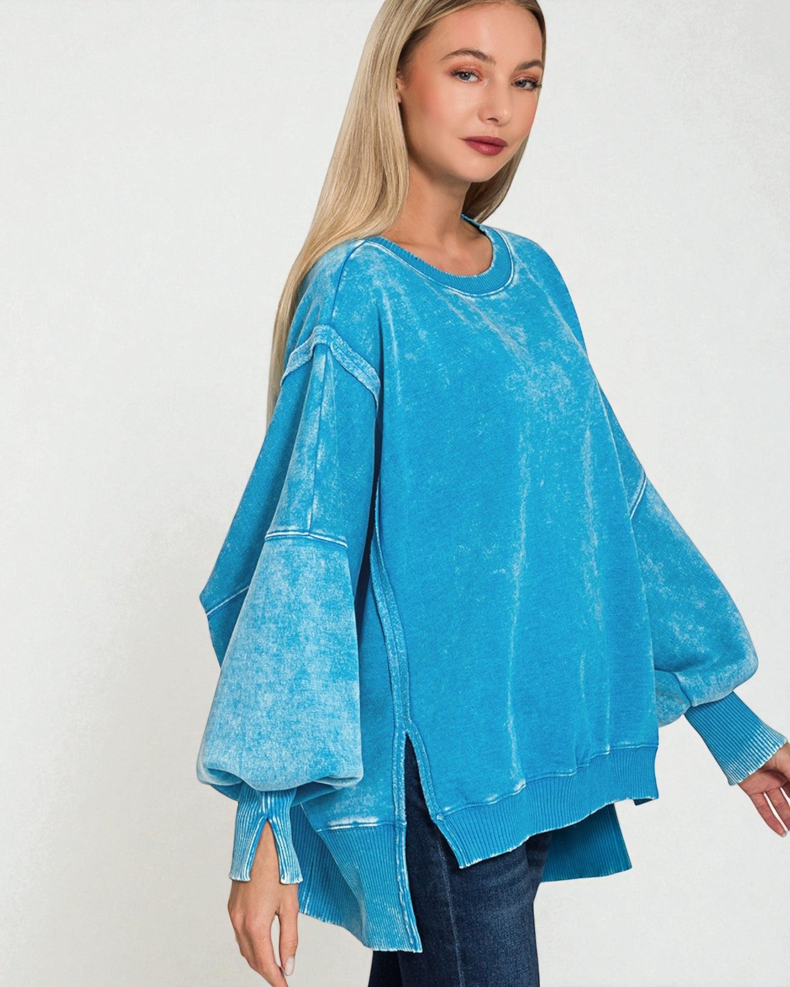Woman wearing a blue acid-wash sweater on a white background