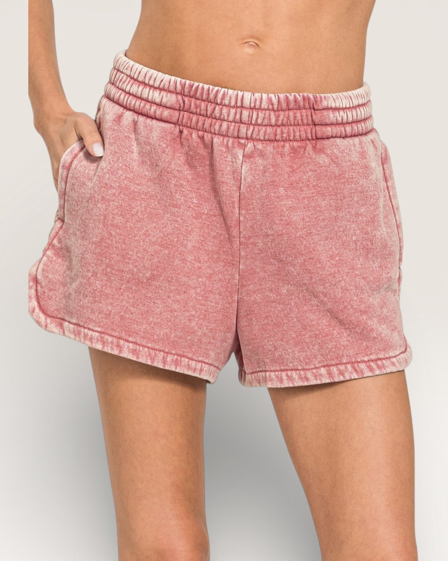 Pink shorts worn by a person on a plain background