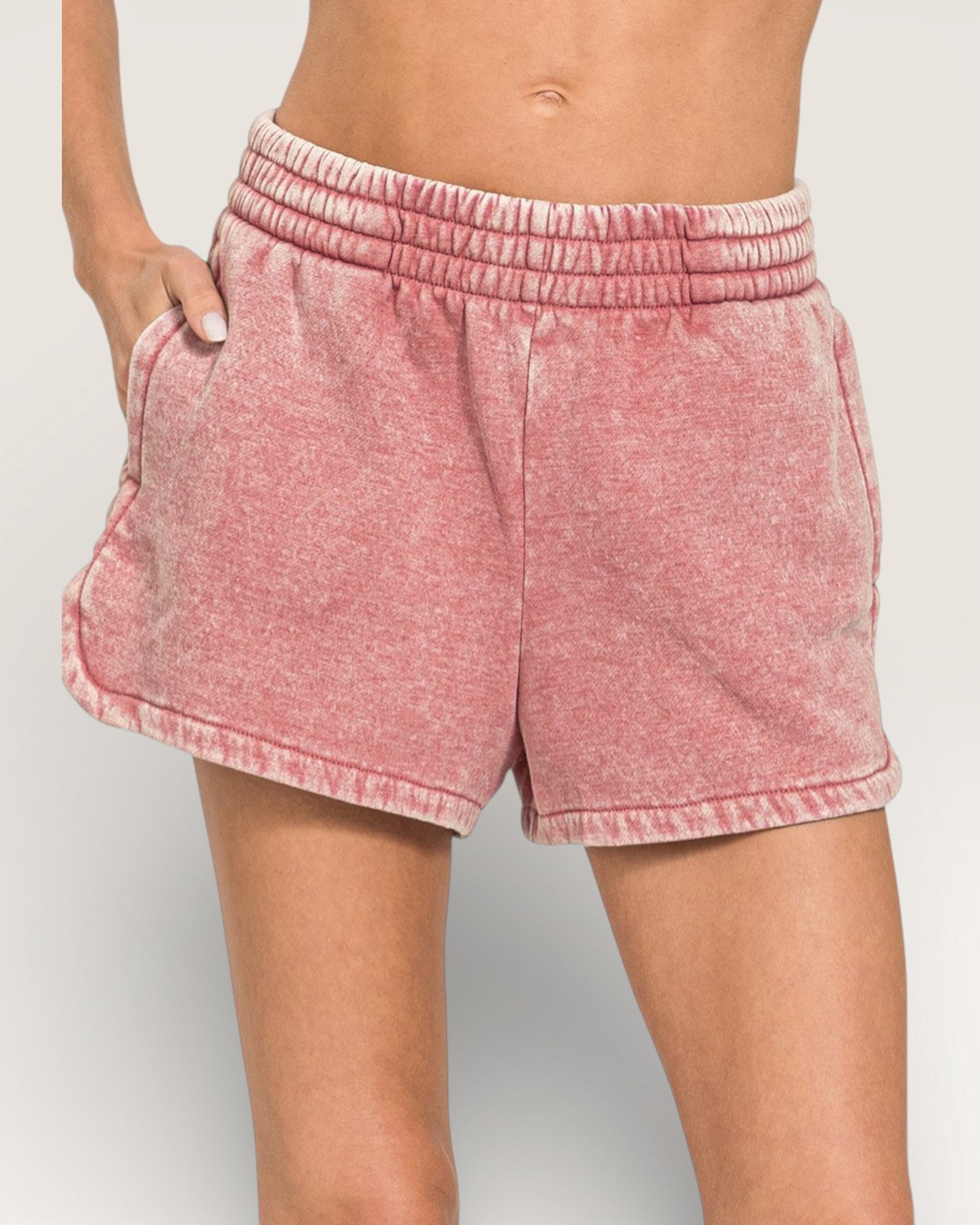 Pink shorts worn by a person on a plain background