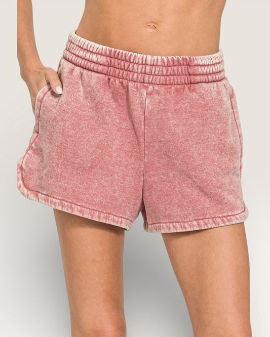 Pink shorts worn by a person on a plain background