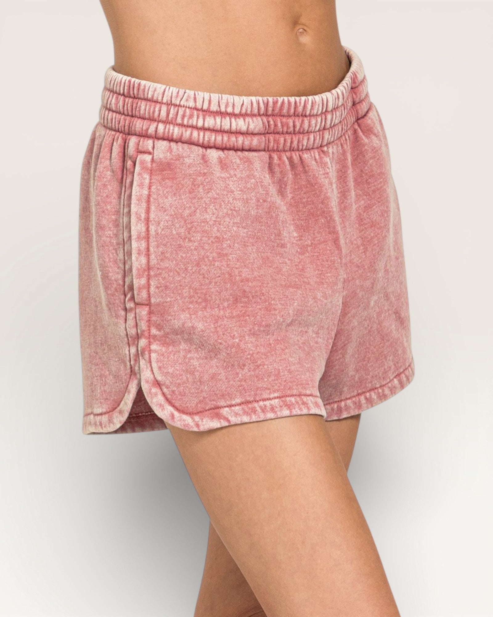 Pink shorts worn by a person on a white background