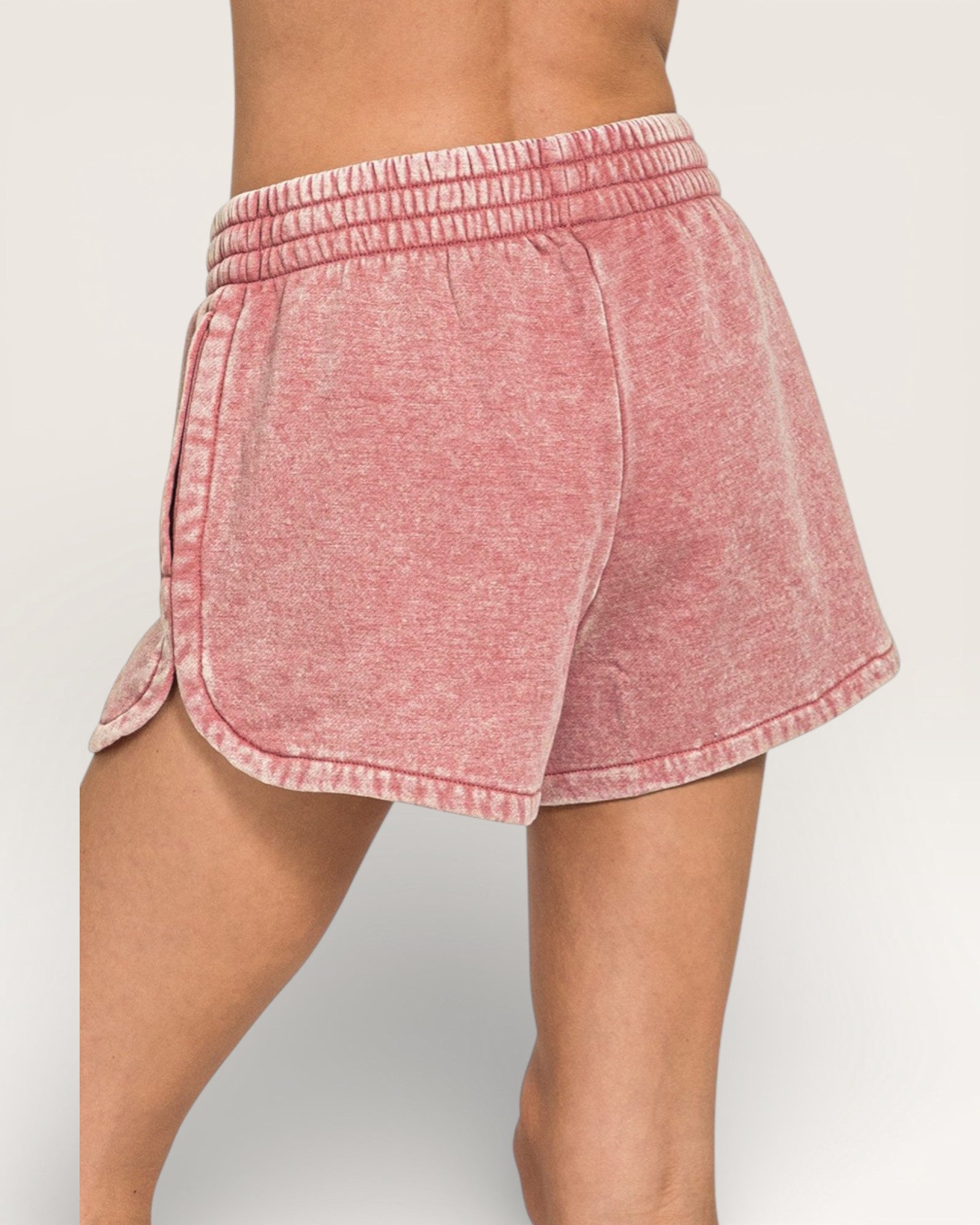 Pink shorts worn by a person on a plain background
