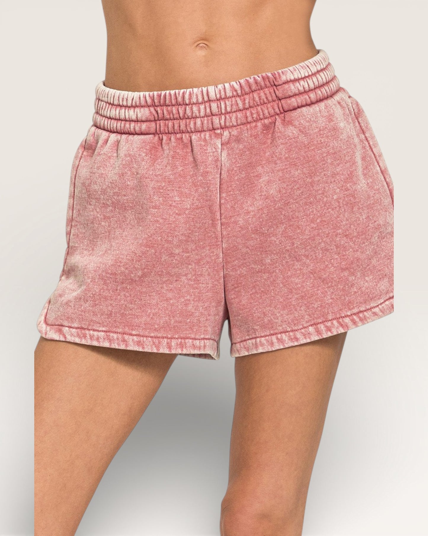 Pink shorts worn by a person on a plain background