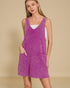 Woman wearing a purple denim dress against a beige background