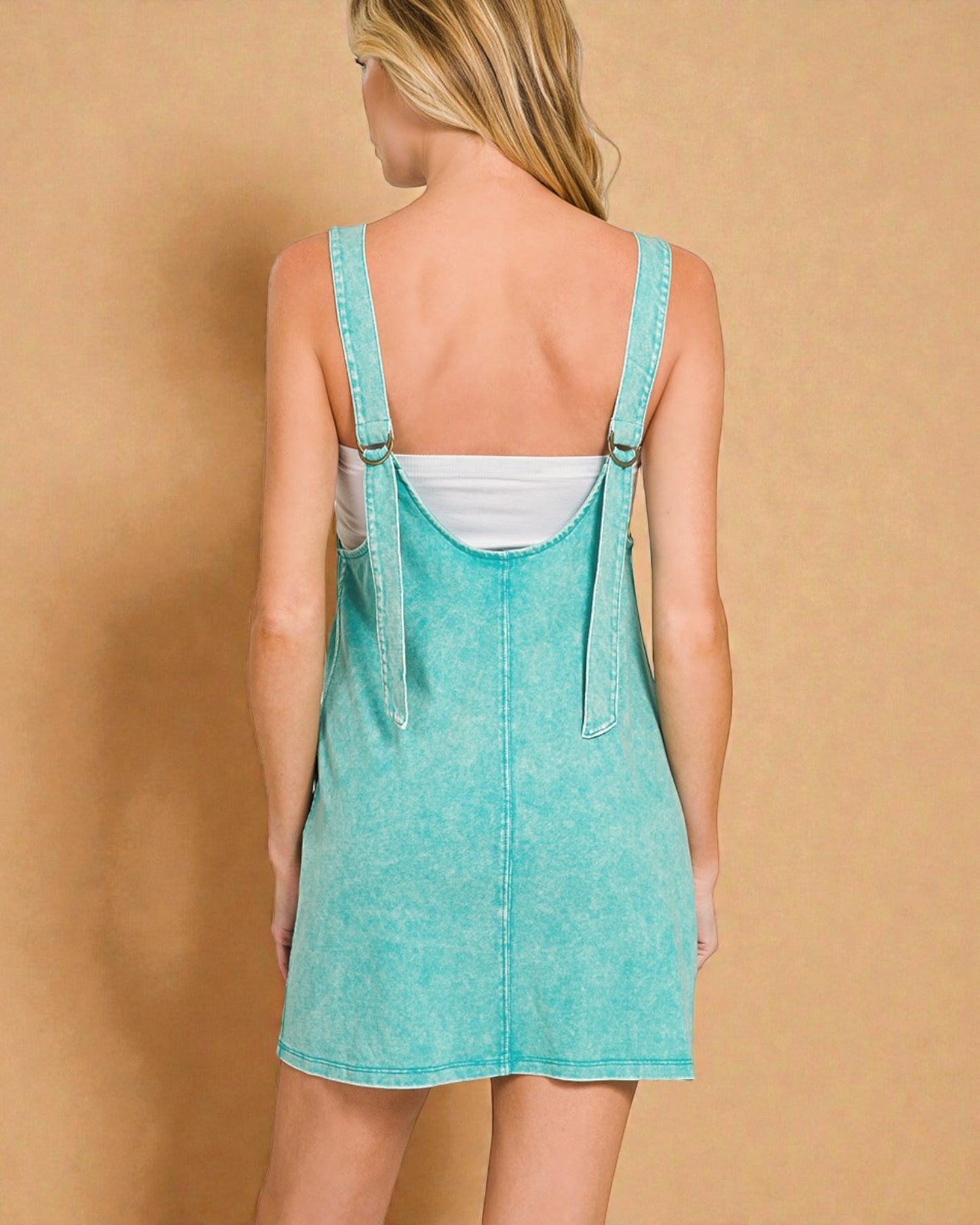 Person wearing a turquoise denim dress against a beige background