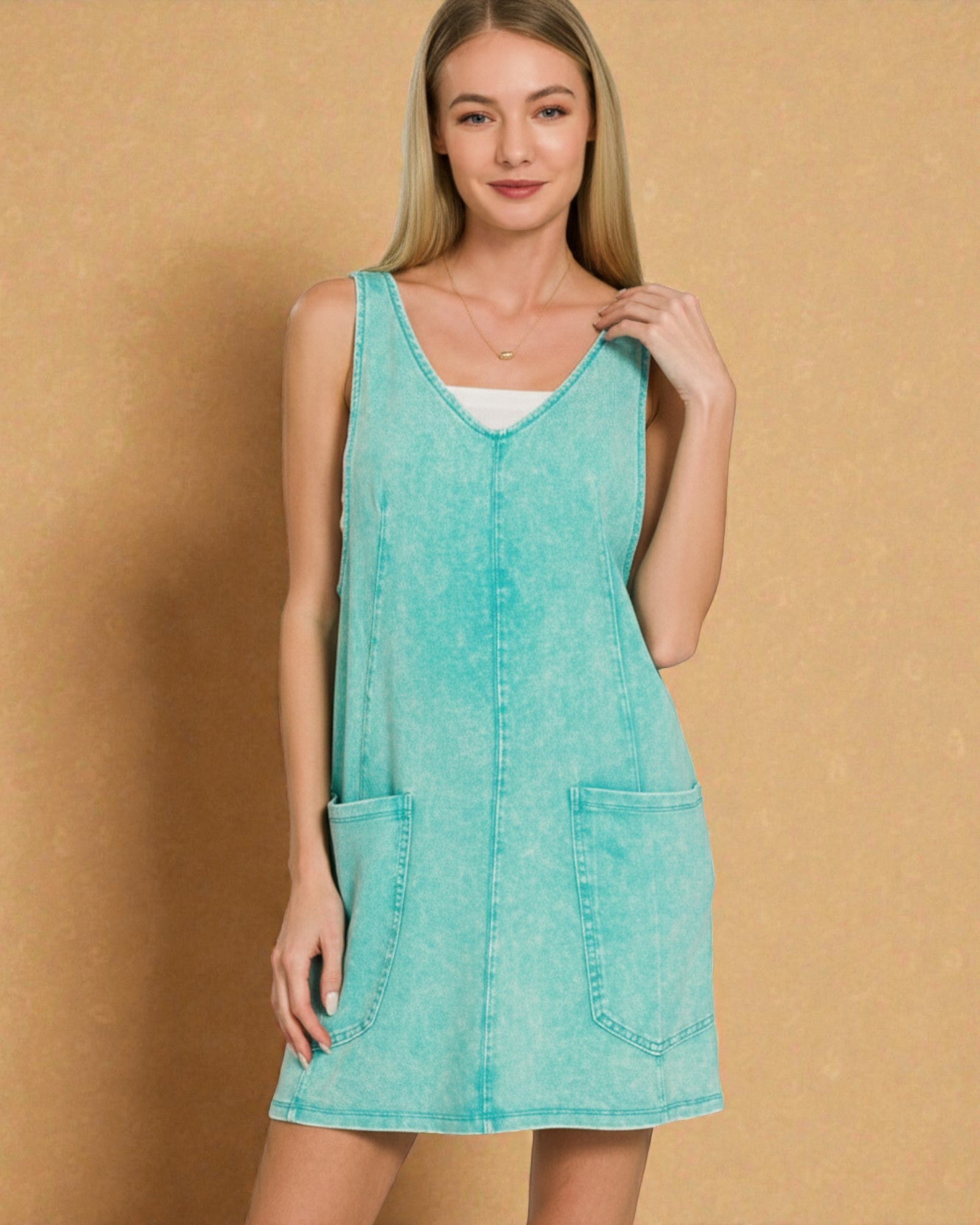 Woman wearing a turquoise sleeveless dress against a beige background