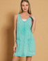Woman wearing a turquoise sleeveless dress against a beige background