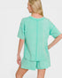 Person wearing a mint green pajama set on a white background
