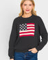 Woman wearing a black sweater with an American flag design on a white background