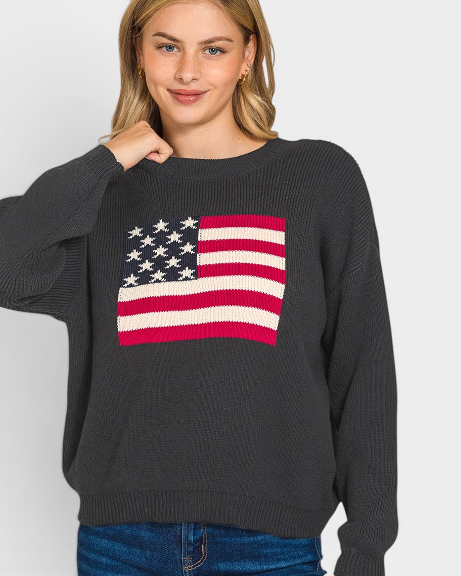Person wearing a black sweater with an American flag design on a plain background