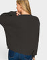Person wearing a black sweater and blue jeans on a white background