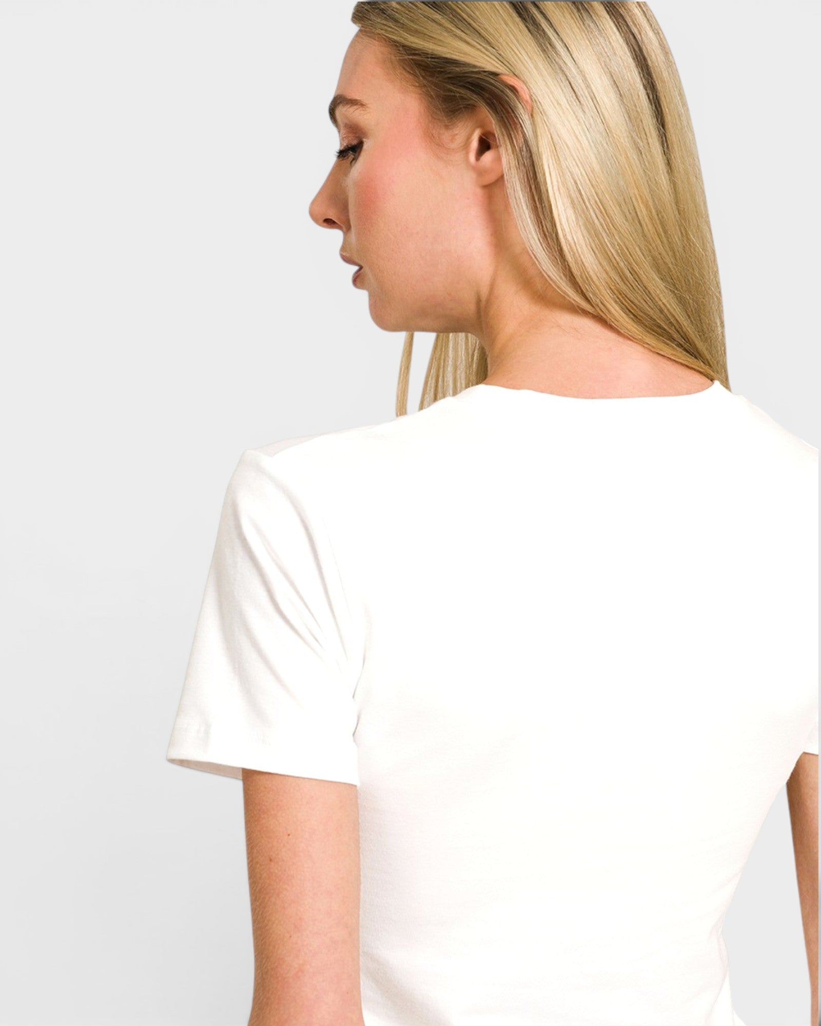 Woman wearing a plain white t-shirt against a light gray background