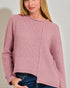 Woman wearing a pink knitted cardigan against a plain background