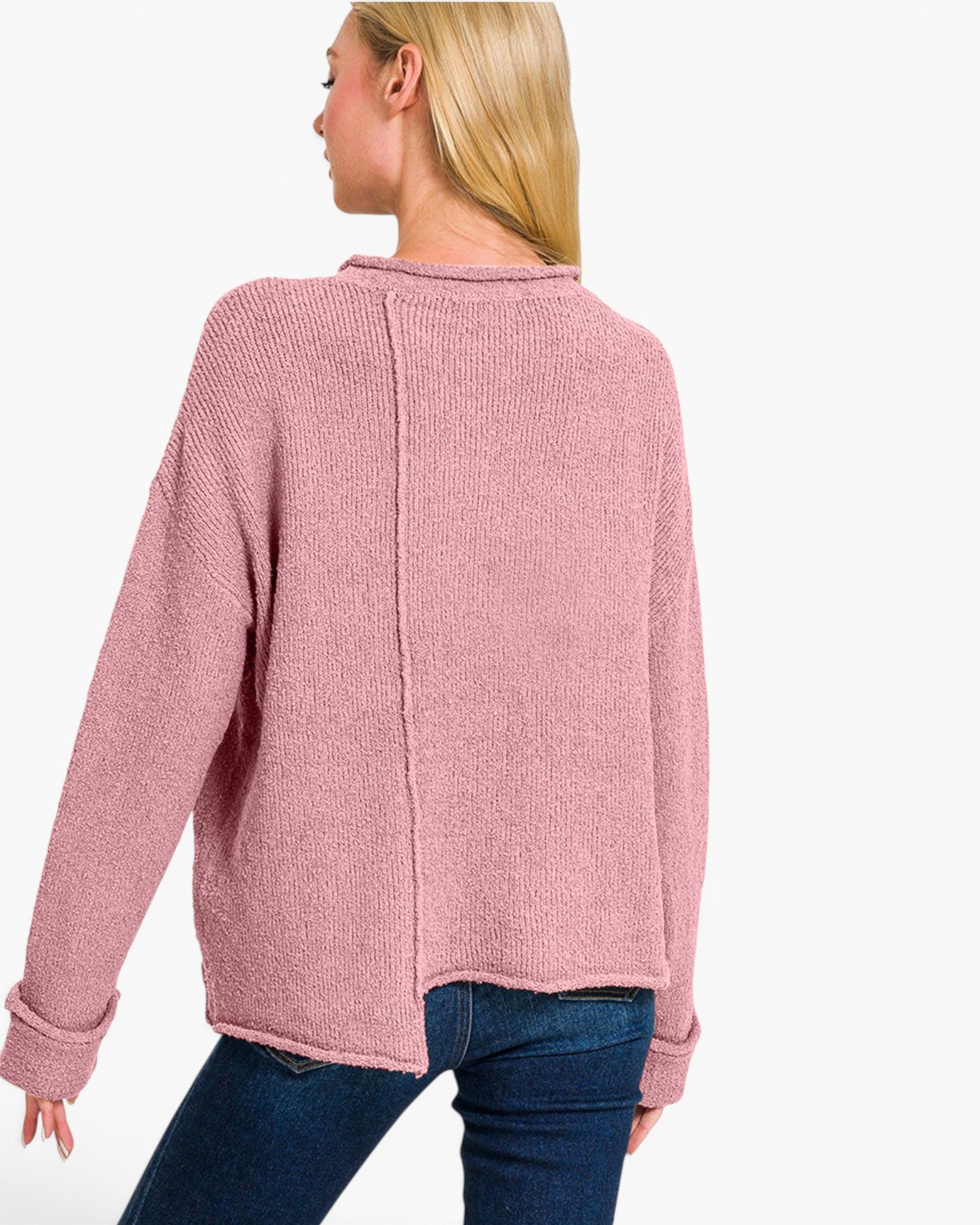 A woman shown from the back wearing a dusty pink ribbed knit sweater and blue jeans against a plain white background.