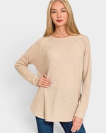 Woman wearing a beige long-sleeve top against a white background