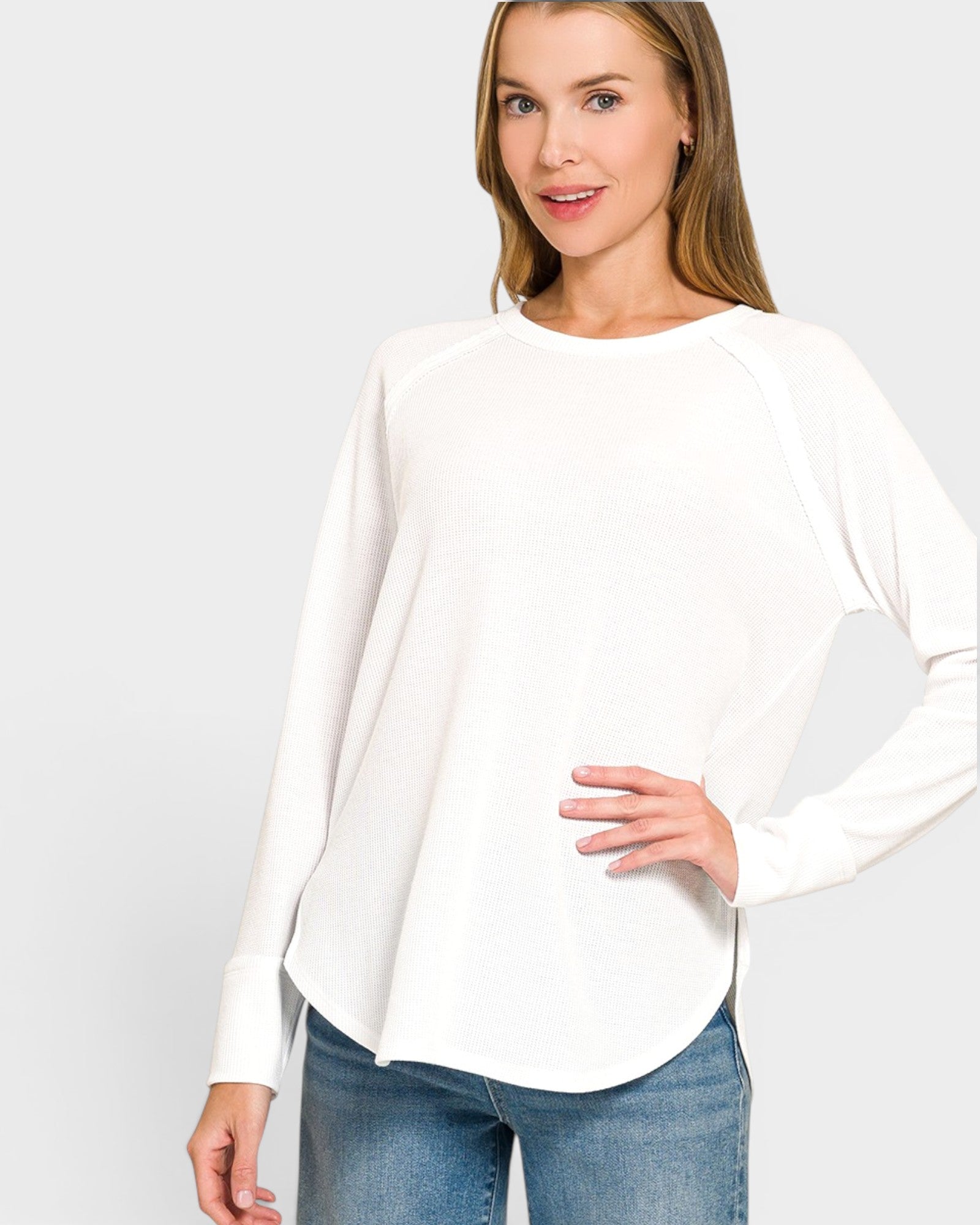 Woman wearing a white blouse and blue jeans on a plain background