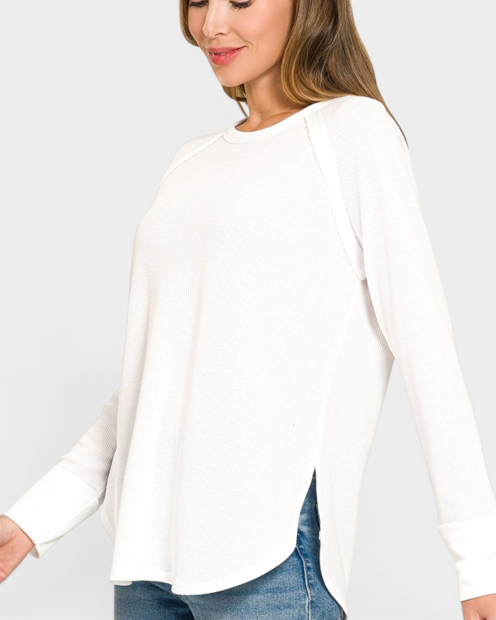 Woman wearing a white blouse with long sleeves on a plain background