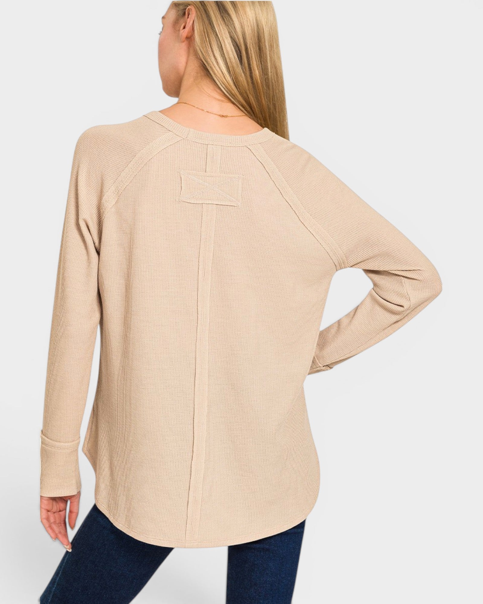 Beige long-sleeve top worn by a person on a white background