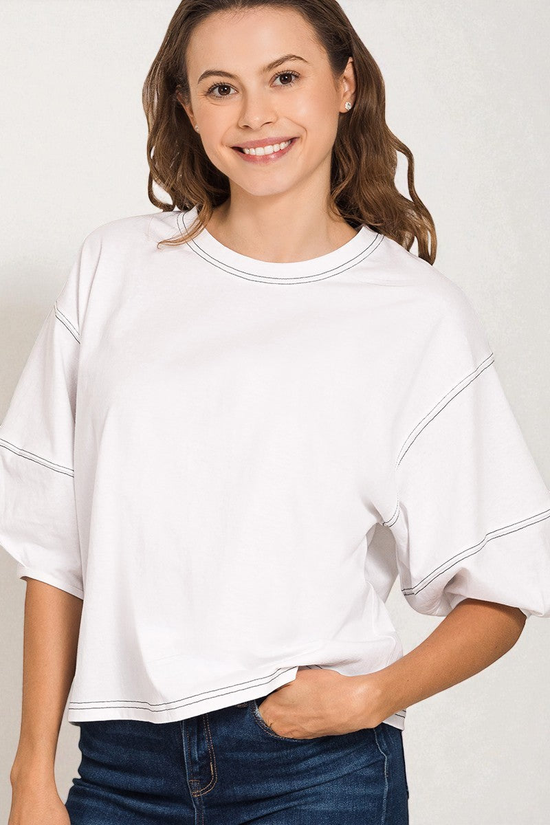 Woman wearing a white oversized shirt and blue jeans on a plain background