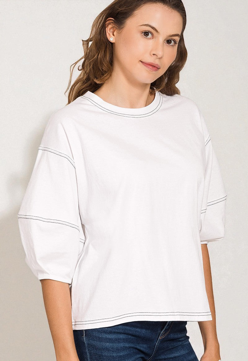 Woman wearing a white oversized sweatshirt against a plain background