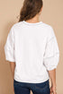 Person wearing a white oversized shirt with blue jeans on a beige background