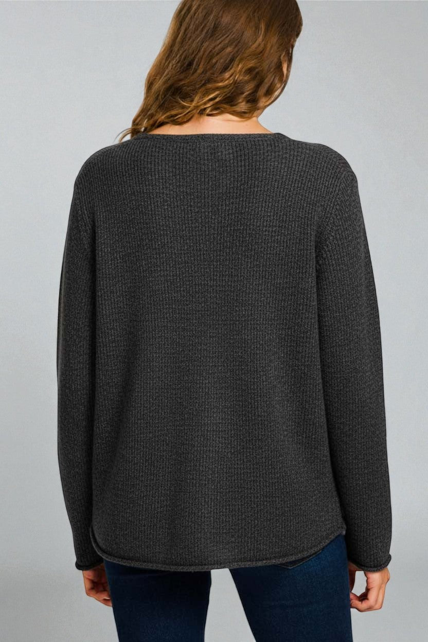 Person wearing a dark gray sweater on a plain background