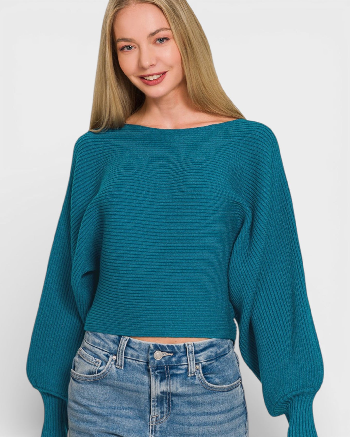 Woman wearing a teal sweater and blue jeans on a white background