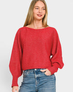 Woman wearing a red sweater and blue jeans on a plain background