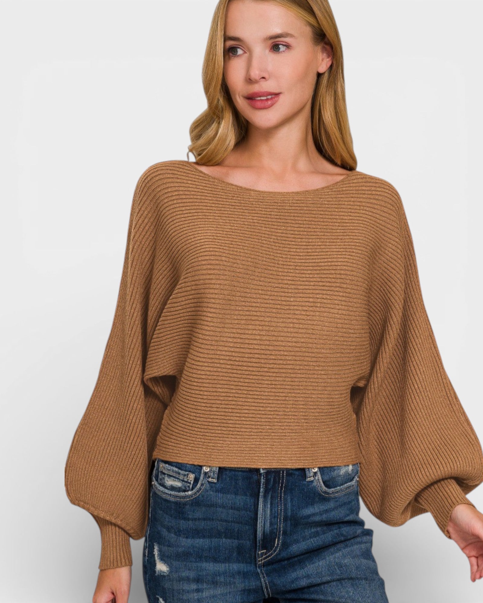 Woman wearing a brown sweater and blue jeans on a white background