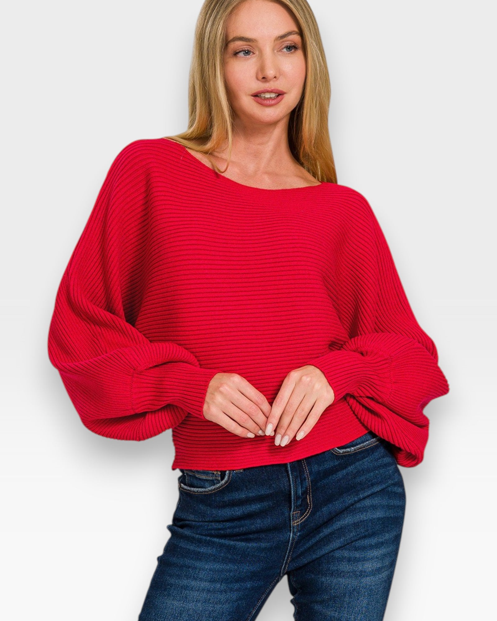 Woman wearing a red sweater and blue jeans against a white background