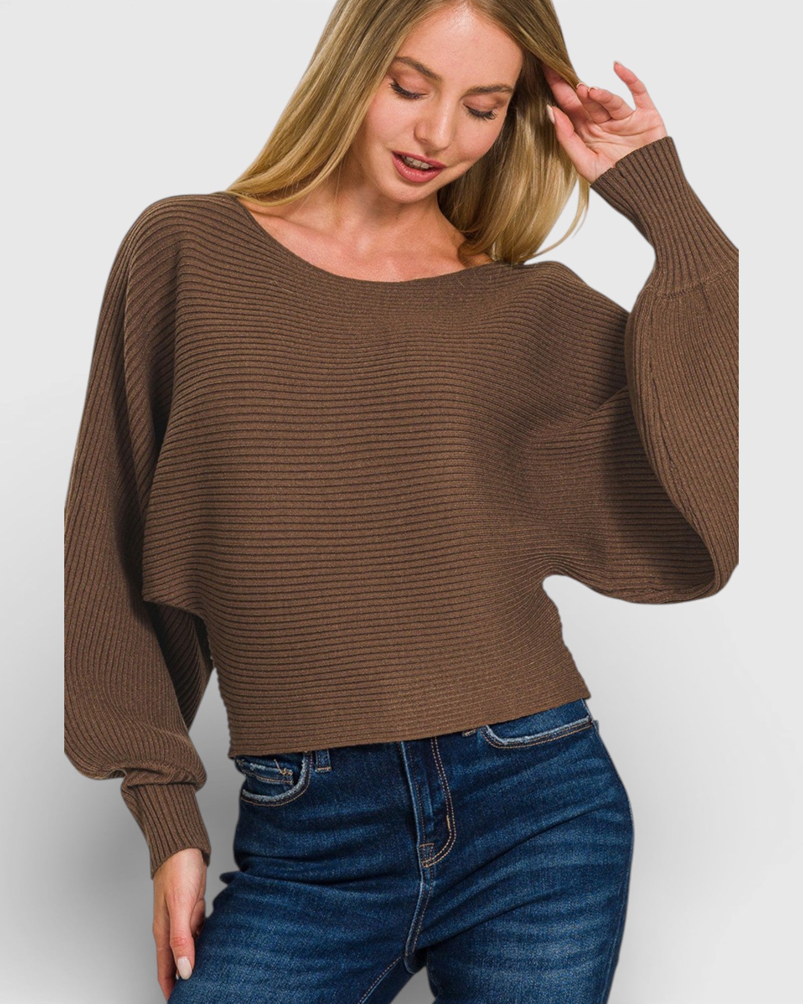 Woman wearing a brown sweater and blue jeans on a white background