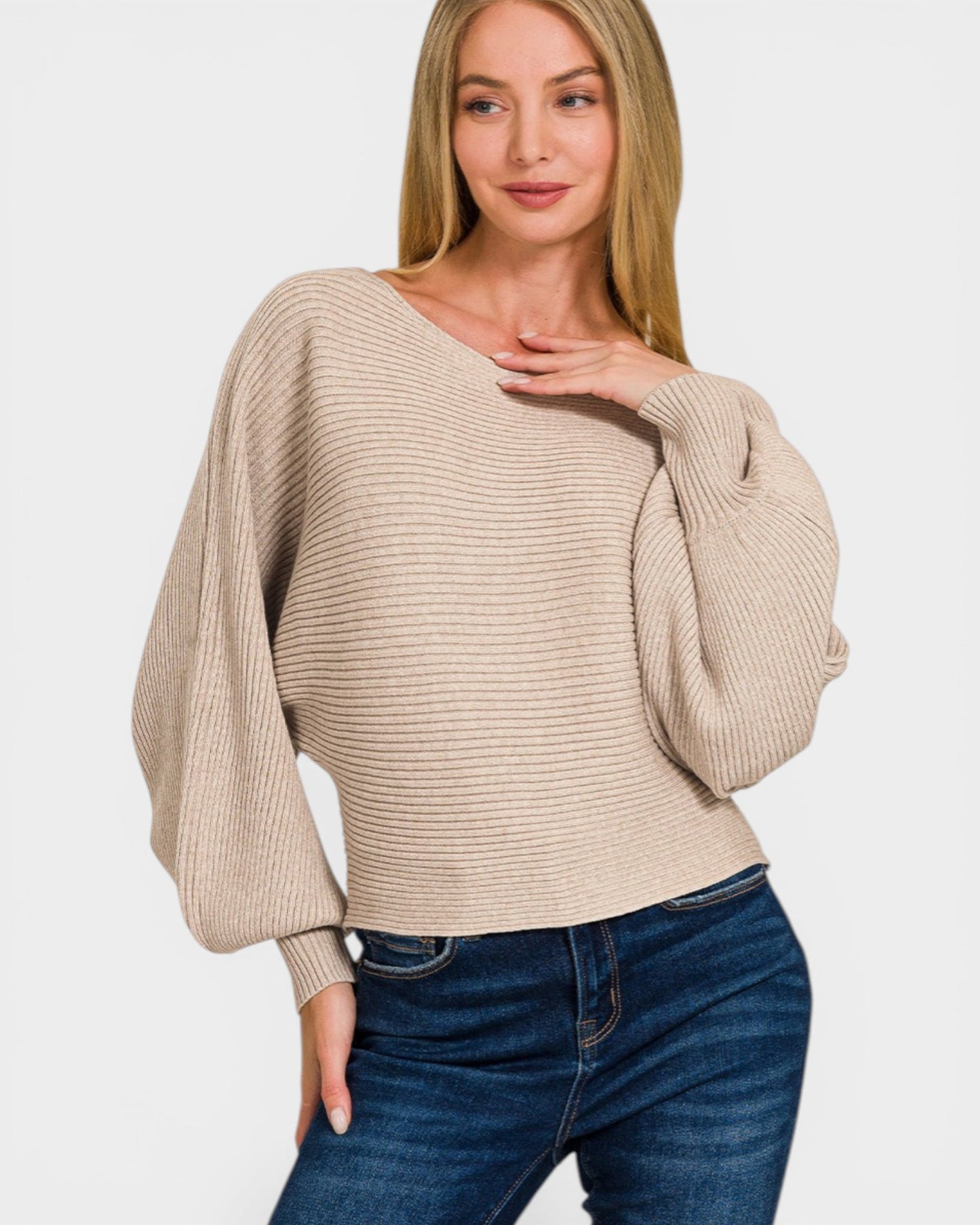 Woman wearing a beige sweater and blue jeans on a white background