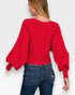 Person wearing a red sweater with balloon sleeves on a white background