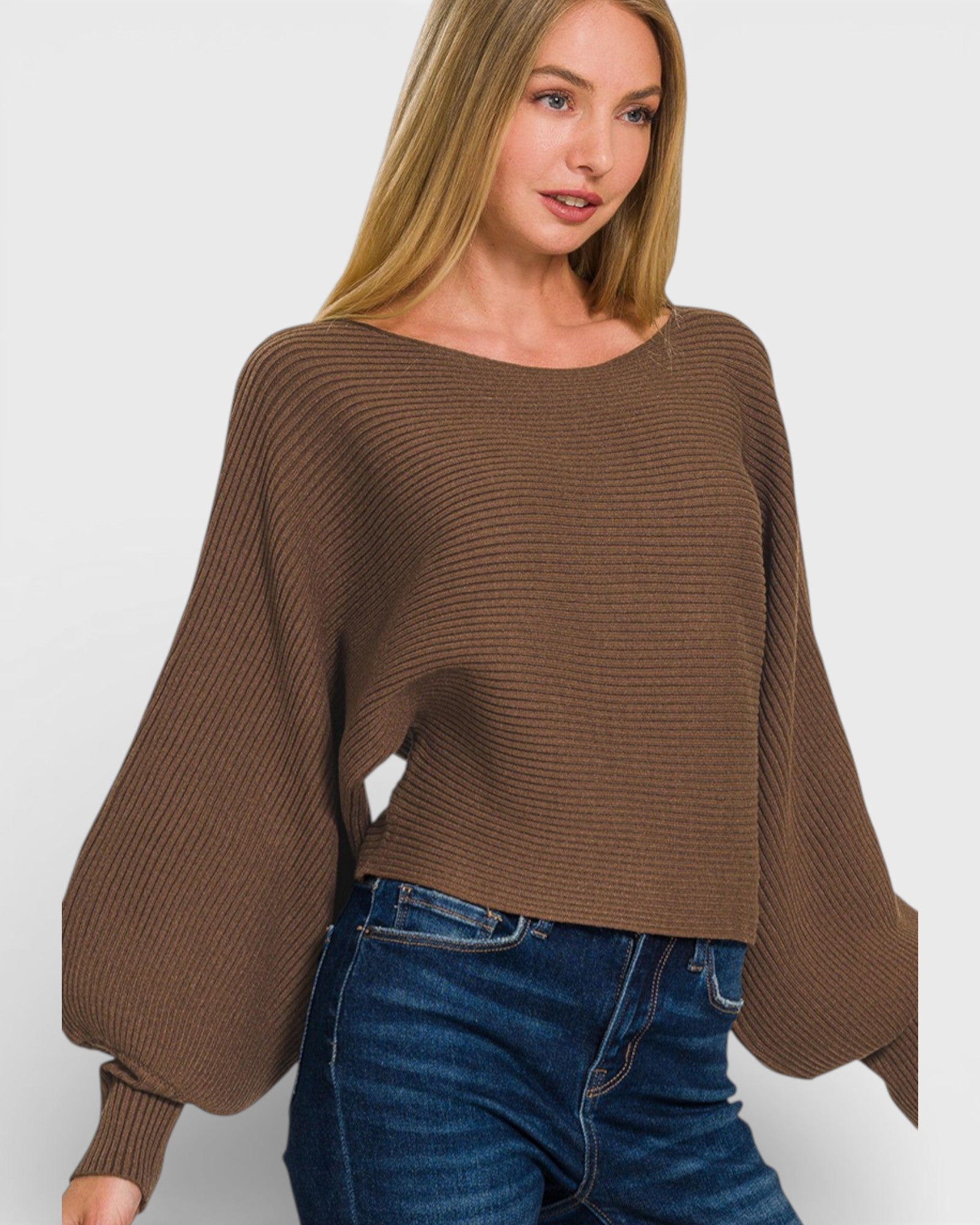 Woman wearing a brown sweater and blue jeans on a white background