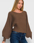 Woman wearing a brown sweater and blue jeans on a white background