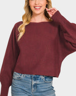 Woman wearing a burgundy sweater and blue jeans on a white background